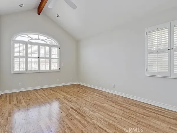 an empty room with wooden floor cabinet and windows