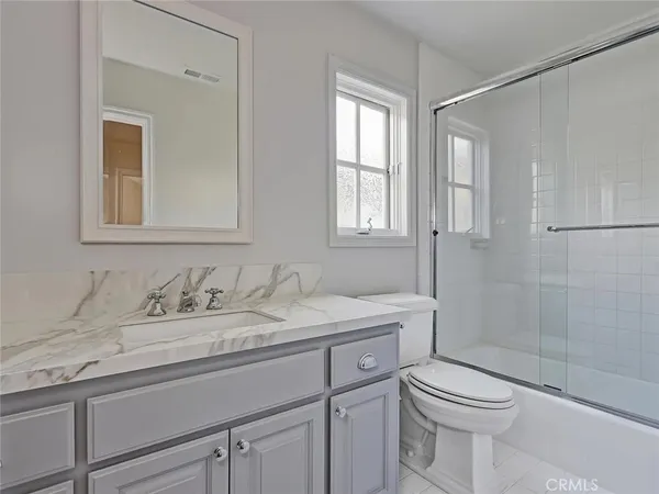 a bathroom with a granite countertop sink a toilet and shower