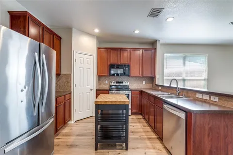 a kitchen with stainless steel appliances granite countertop refrigerator stove top oven and sink