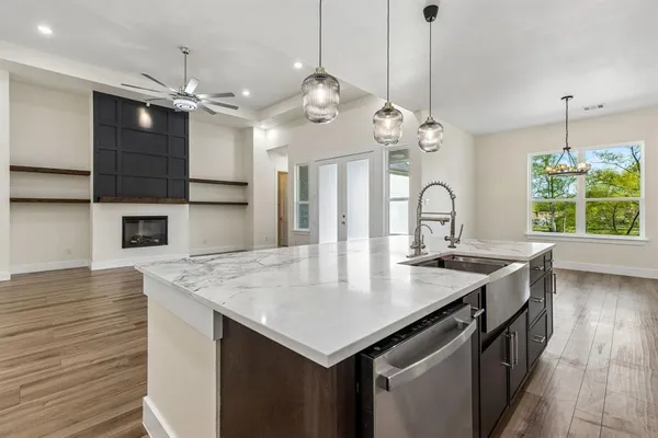 a kitchen with a stove a kitchen island a sink dishwasher a dining table and chairs with wooden floor
