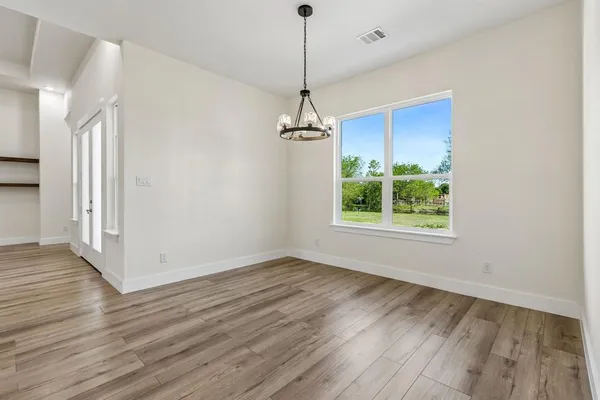 a view of a room with wooden floor a ceiling fan and windows