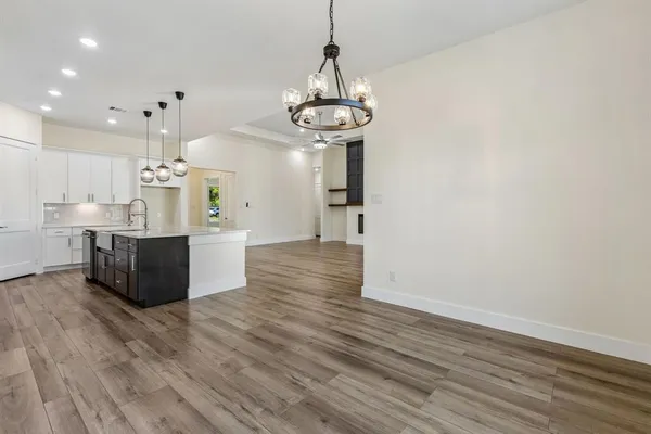 a view of a kitchen with granite countertop wooden floor stainless steel appliances and a chandelier
