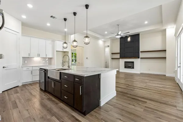 a kitchen with stainless steel appliances granite countertop wooden floors wooden cabinets a sink and a island