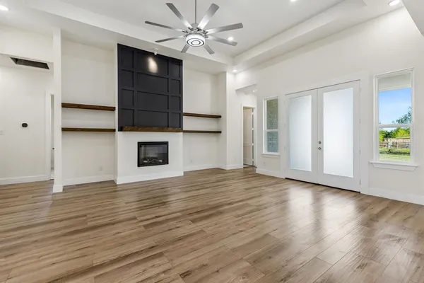 a view of empty room with wooden floor and fan