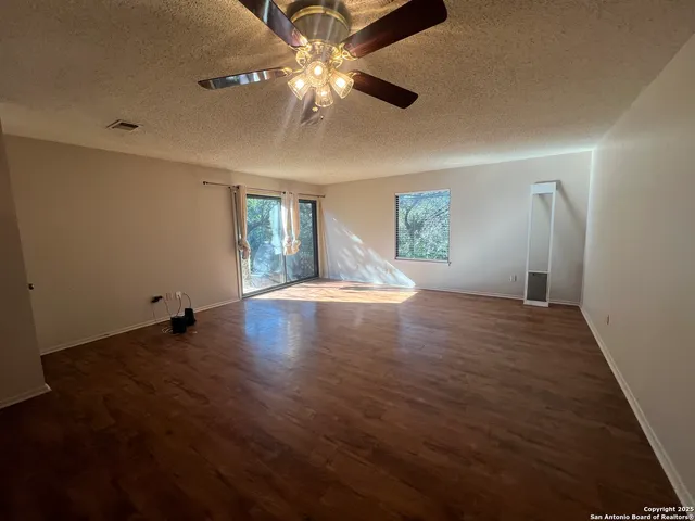a view of an empty room with window and wooden floor