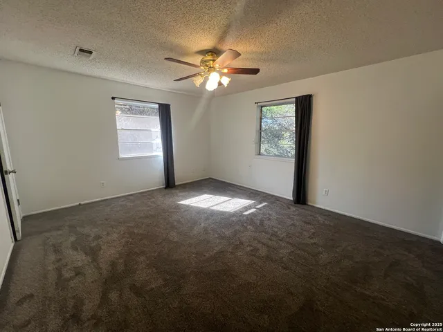an empty room with windows and fan