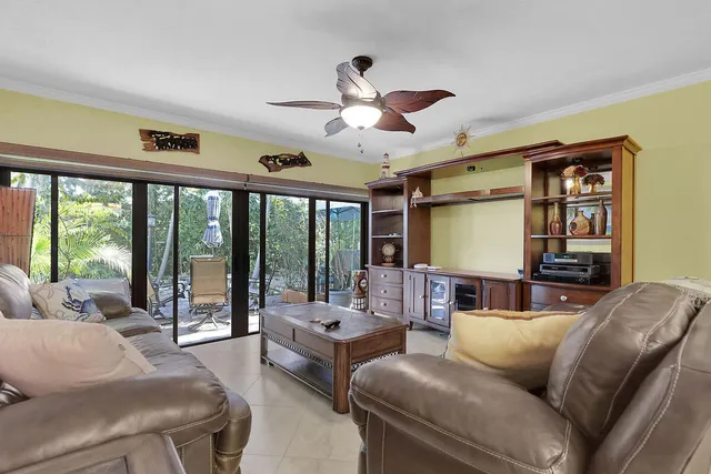 a living room with furniture a ceiling fan and a large window