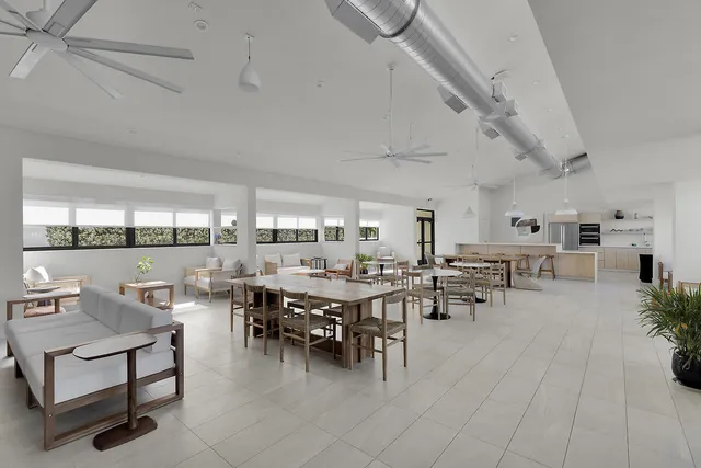 a room with lots of tables a large window and chairs