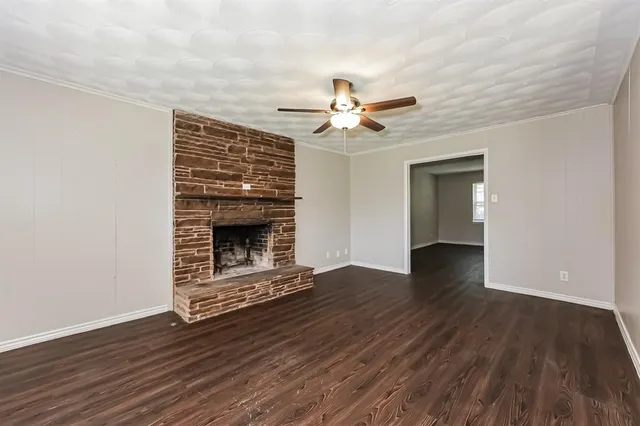 a view of an empty room with wooden floor fireplace and a window