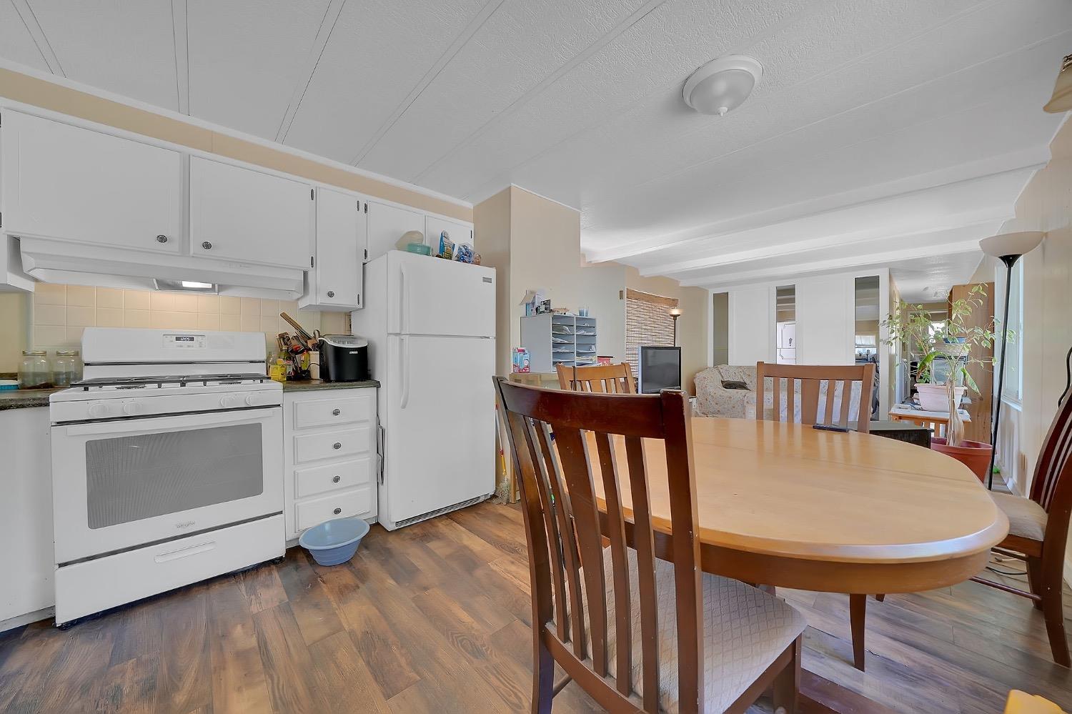 150 Clinton Road, Unit 38 Jackson, CA 95642 - Photo 12 of 18 a kitchen with stainless steel appliances kitchen island granite countertop a stove a refrigerator a dining table and chairs with wooden floor