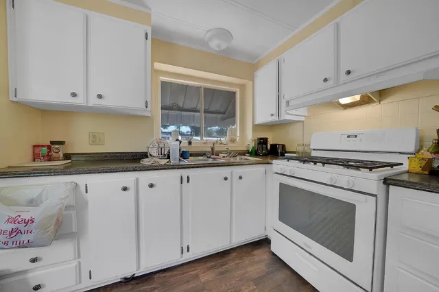 a kitchen with granite countertop white cabinets and white appliances