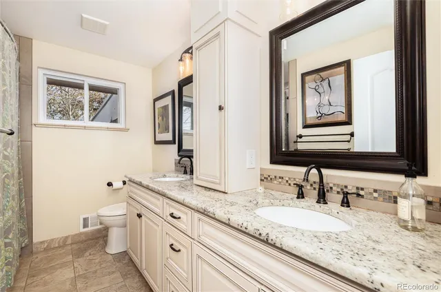 a bathroom with a granite countertop sink mirror vanity and toilet