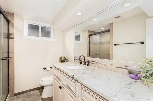 a bathroom with a granite countertop sink a toilet and a mirror