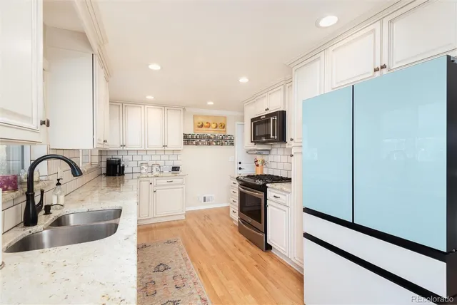 a kitchen with stainless steel appliances granite countertop a refrigerator sink and white cabinets