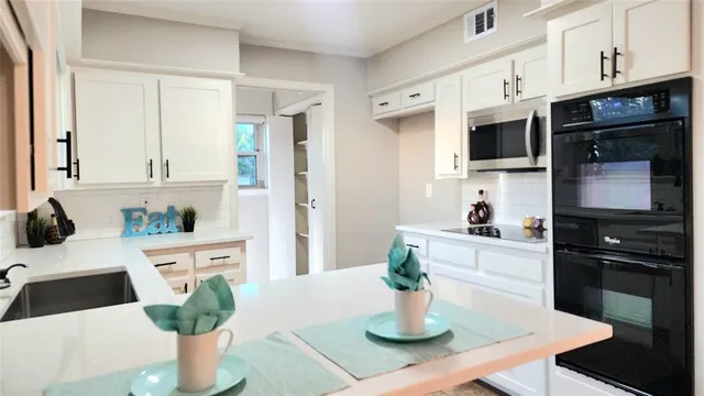 a kitchen with stainless steel appliances kitchen island granite countertop a refrigerator a stove a sink a dining table and chairs