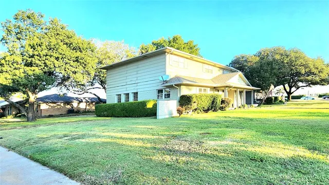 a view of a house with a big yard and large trees