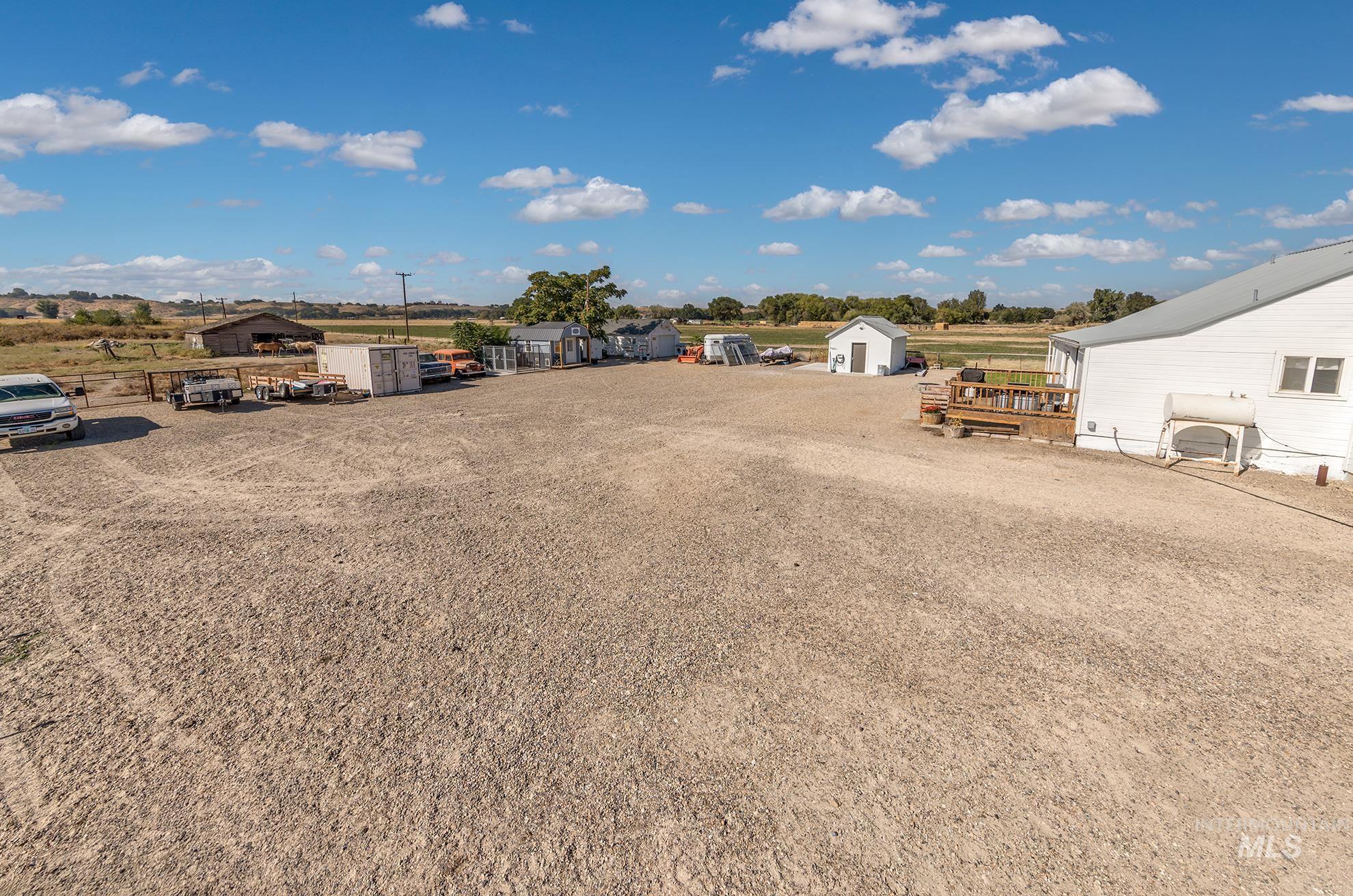 4631 Rolland Road Ontario, OR 97914 - Photo 26 of 43 Expansive gravel lot with multiple outbuildings, a detached white structure, and a wood deck