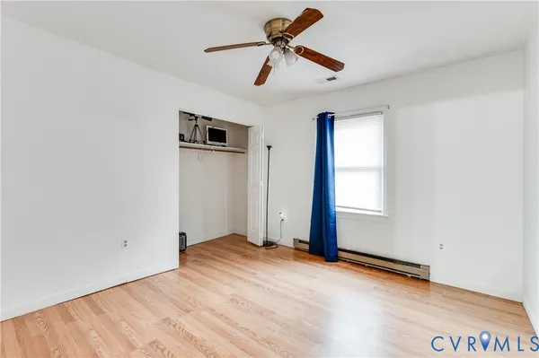 a view of empty room with wooden floor and ceiling fan