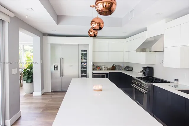 a kitchen with stainless steel appliances a stove a chimney a sink and white cabinets