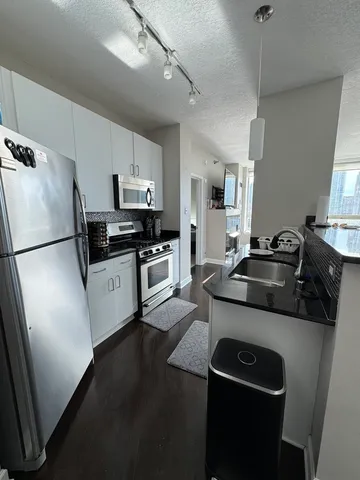 a kitchen with stainless steel appliances granite countertop a refrigerator a stove a sink dishwasher and a refrigerator