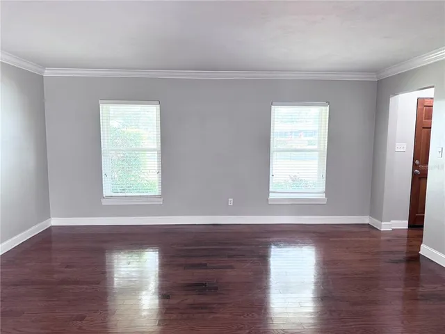 an empty room with wooden floor & windows