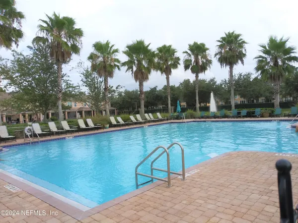 a view of a swimming pool with a patio and palm trees