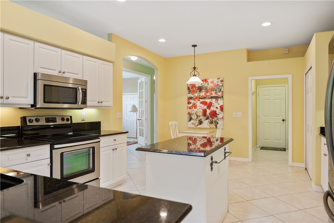 412 North Tangerine Square Southwest Vero Beach, FL 32968 - Photo 9 of 35 a kitchen with stainless steel appliances kitchen island granite countertop a sink and a stove