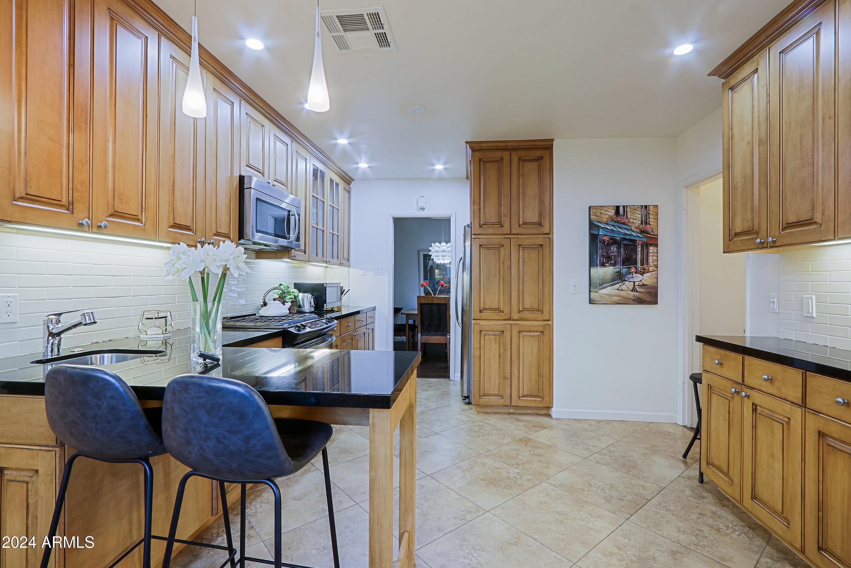 4645 East Windsor Avenue Phoenix, AZ 85008 - Photo 9 of 33 a kitchen with stainless steel appliances granite countertop a table chairs in it and a window