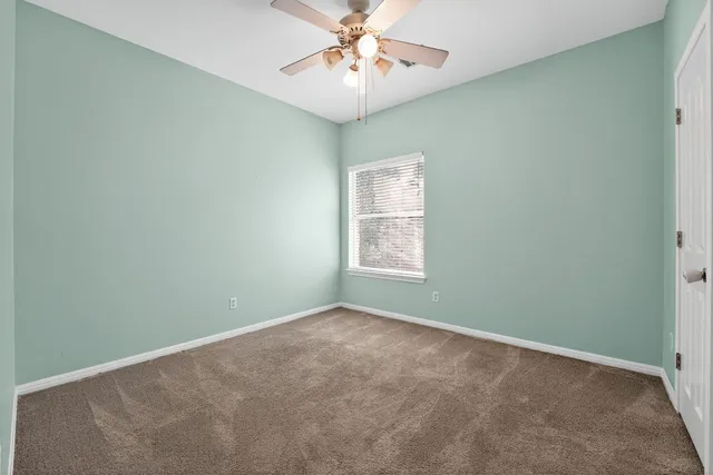 an empty room with a window and a fan