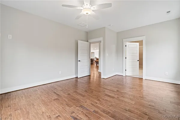 an empty room with wooden floor and ceiling fan