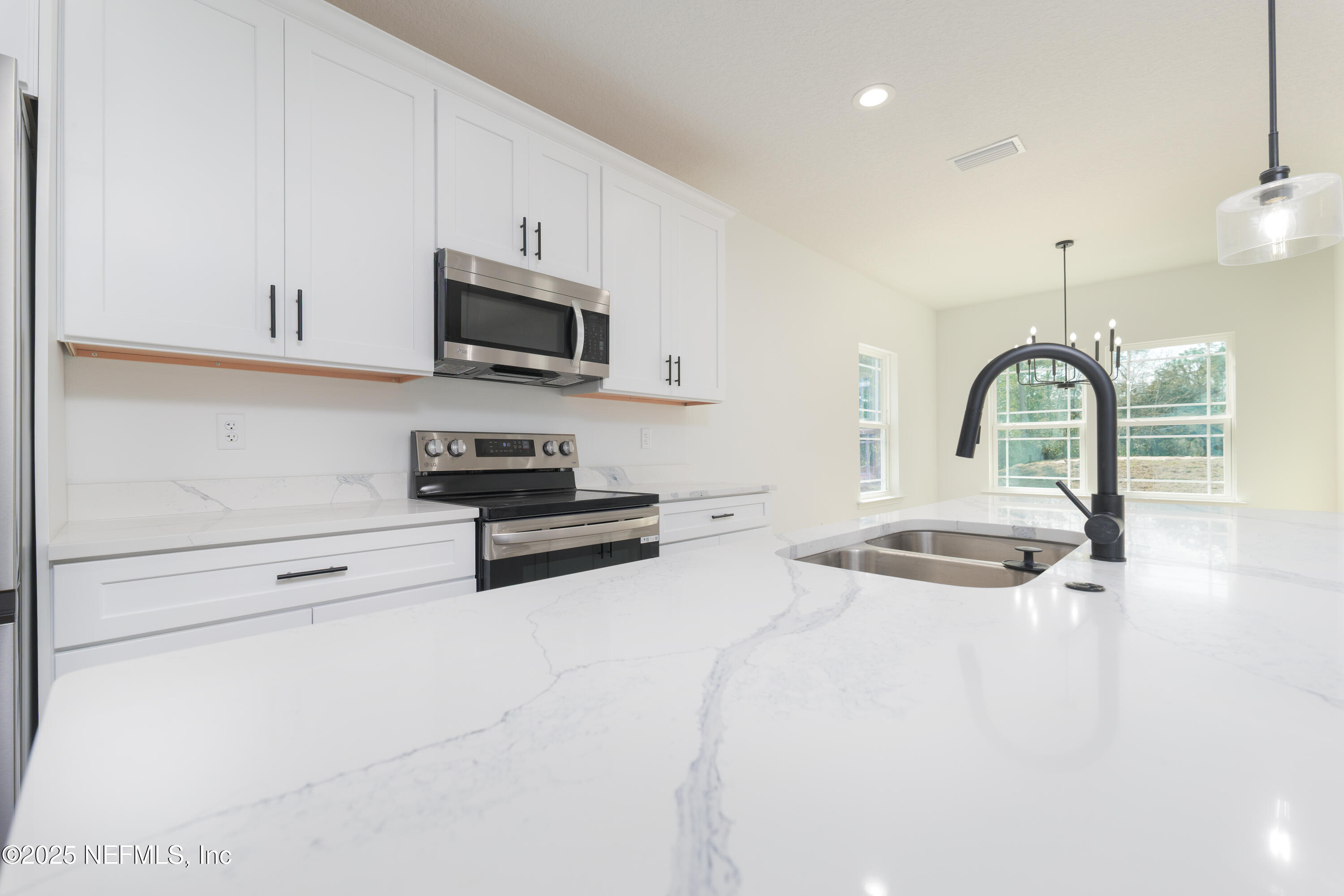 5214 County Road 218 Middleburg, FL 32068 - Photo 11 of 30 a kitchen with stainless steel appliances a stove a sink and white cabinets
