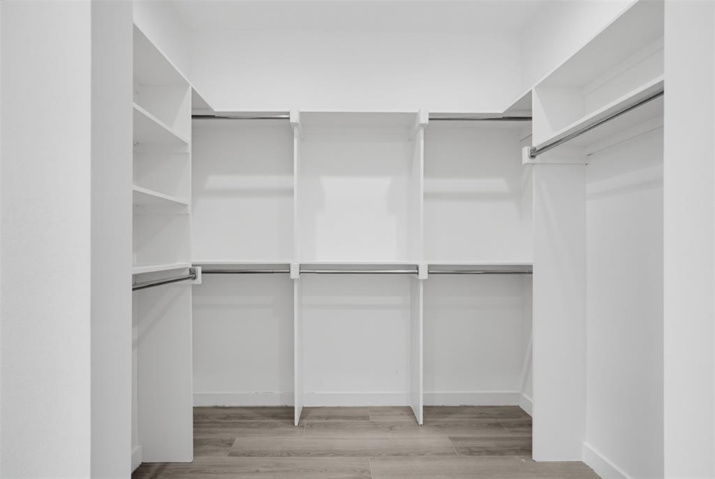 512 South O Connor Road Irving, TX 75060 - Photo 17 of 21 Walk-in closet featuring extensive built-in shelving, multiple hanging rods, and wood-finish flooring