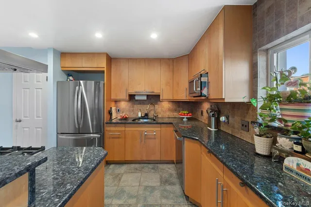 a kitchen with stainless steel appliances granite countertop sink stove refrigerator and cabinets