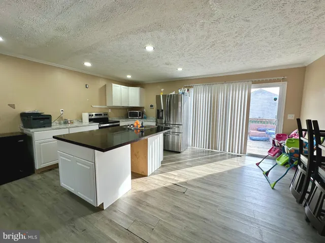 a kitchen with stainless steel appliances kitchen island granite countertop a stove a refrigerator a sink a oven and a microwave with wooden floor