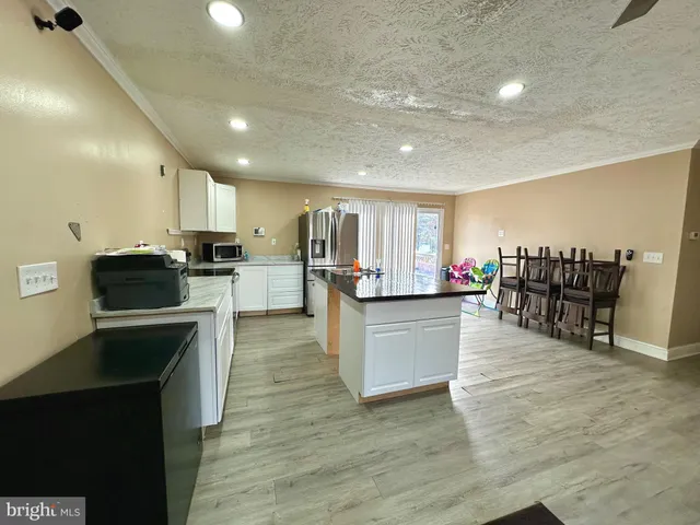 a kitchen with stainless steel appliances kitchen island granite countertop a refrigerator a stove top oven a sink with island and chairs