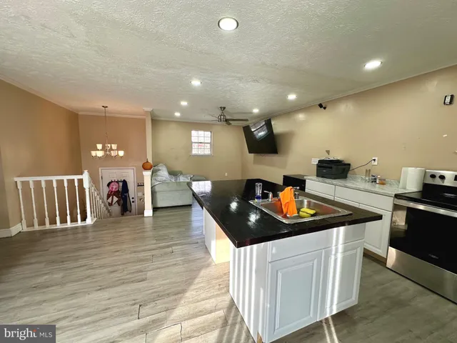 a kitchen with stainless steel appliances granite countertop a stove a sink a refrigerator and white cabinets