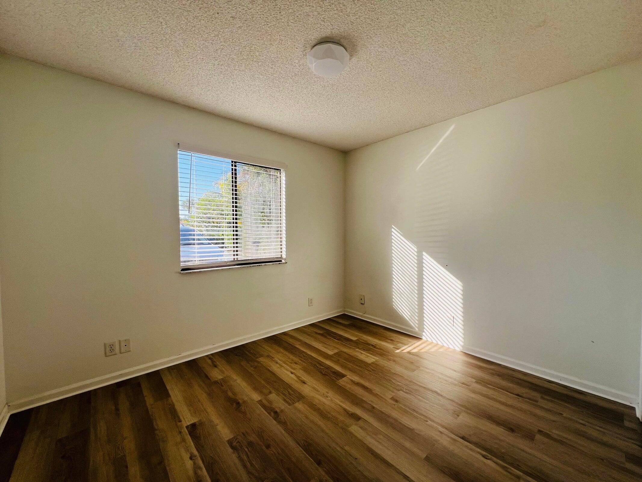 11877 Sturbridge Lane Wellington, FL 33414 - Photo 12 of 20 a view of an empty room with wooden floor and a window