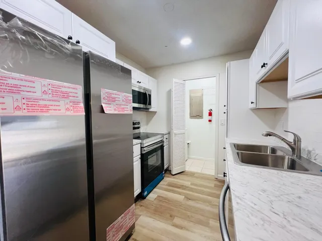 a kitchen with stainless steel appliances a refrigerator a stove a sink and a oven with wooden floor