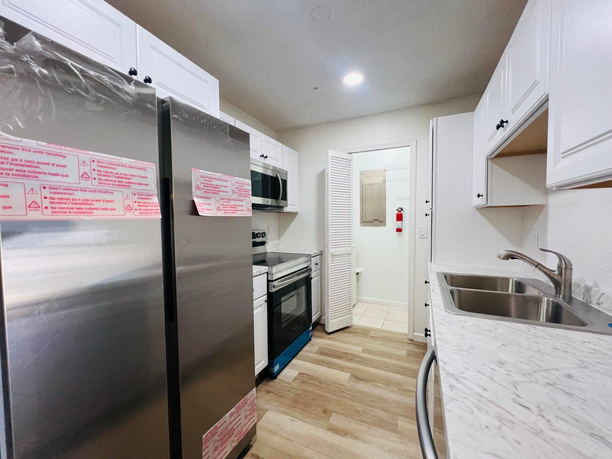 11877 Sturbridge Lane Wellington, FL 33414 - Photo 2 of 20 a kitchen with stainless steel appliances a refrigerator a stove a sink and a oven with wooden floor