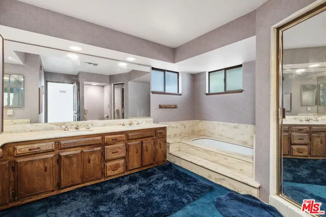 a spacious bathroom with a tub sink and mirror