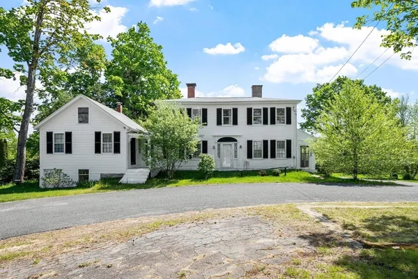 a front view of a house with a garden and trees
