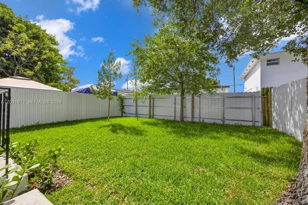 a view of a backyard with large trees and wooden fence