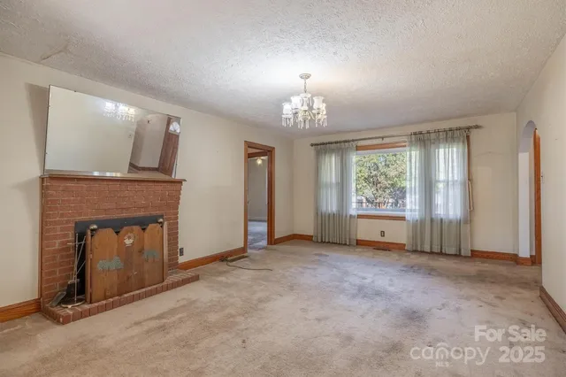 an empty room with windows and fireplace