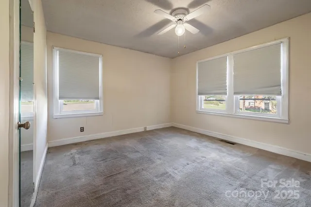 an empty room with windows and fan