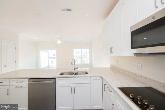 a kitchen with a sink dishwasher a stove and white cabinets with wooden floor