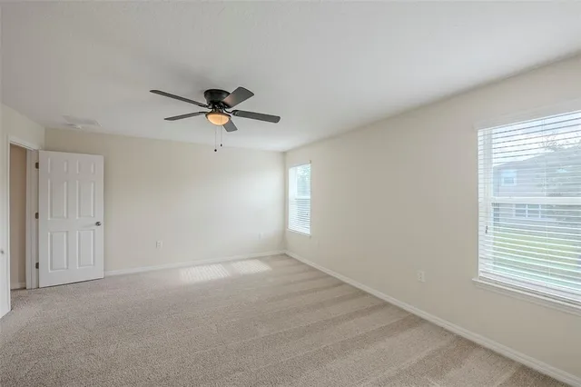 a view of an empty room with a ceiling fan and window