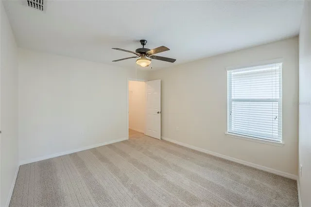 an empty room with a window and a fan