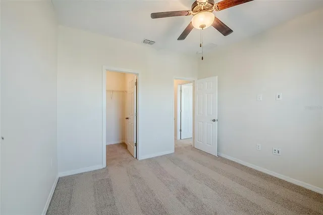 a view of an empty room and chandelier fan
