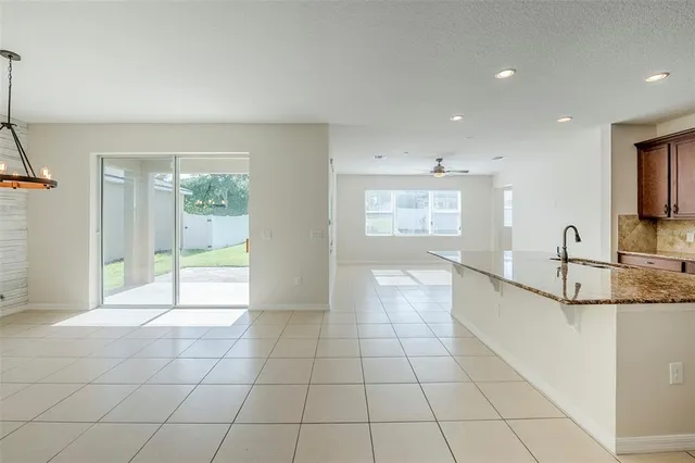 a large white kitchen with granite countertop a large window and a rug