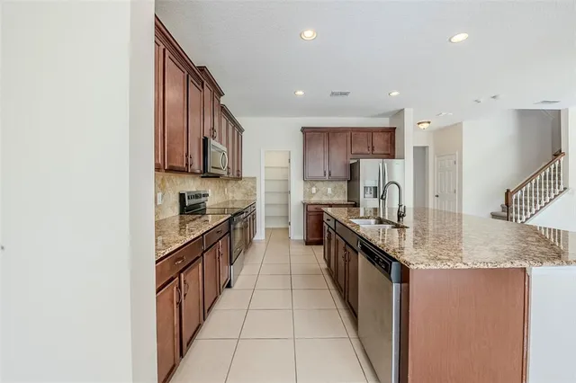 a large kitchen with stainless steel appliances granite countertop a stove top oven a sink and dishwasher